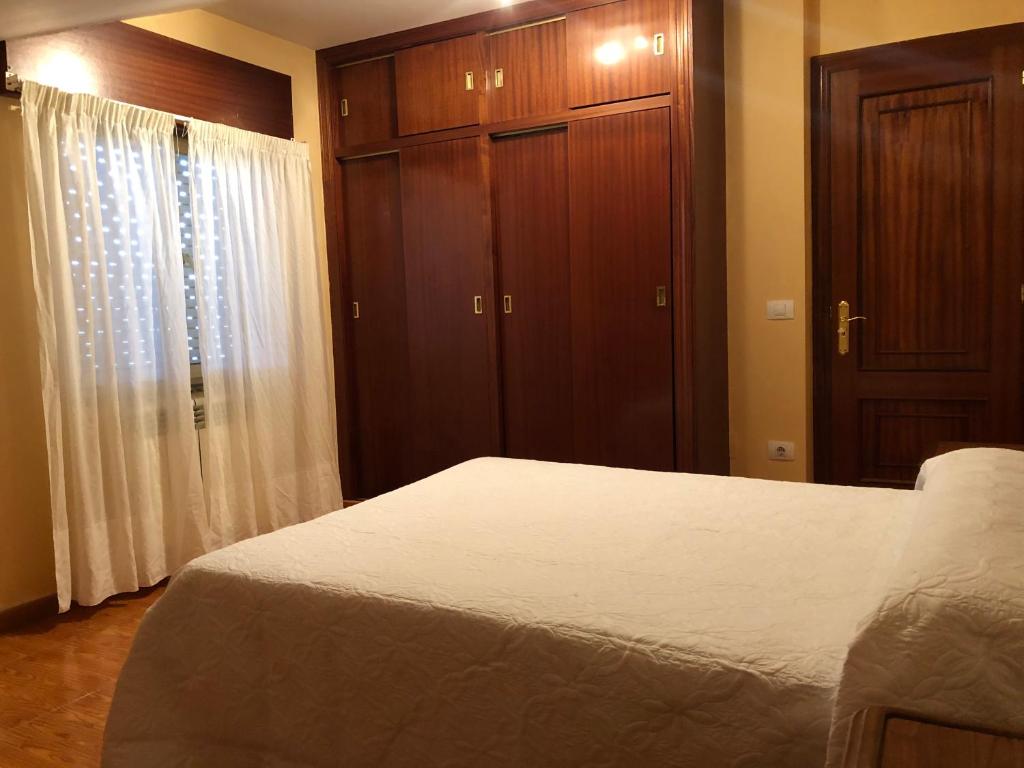 a bedroom with a white bed and wooden cabinets at B&b o barqueiro 2 in O Barqueiro