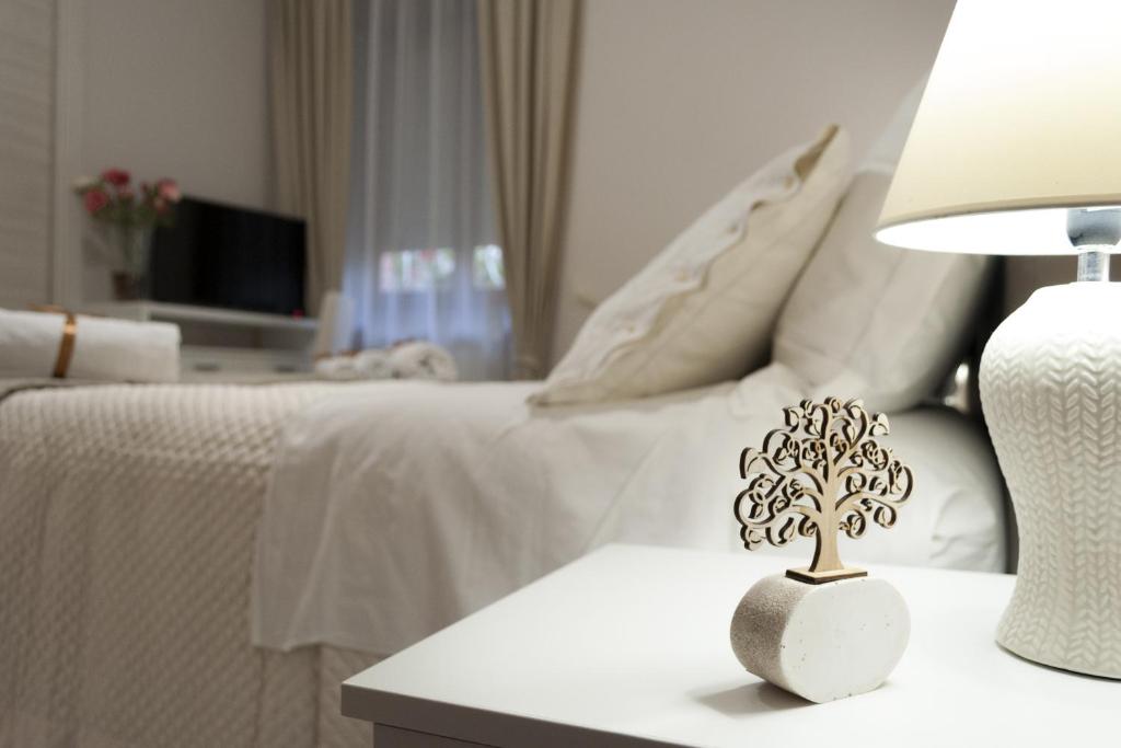 ein weißes Bett mit einem Tisch und einem Baum darauf in der Unterkunft L' albero di giada in Caserta