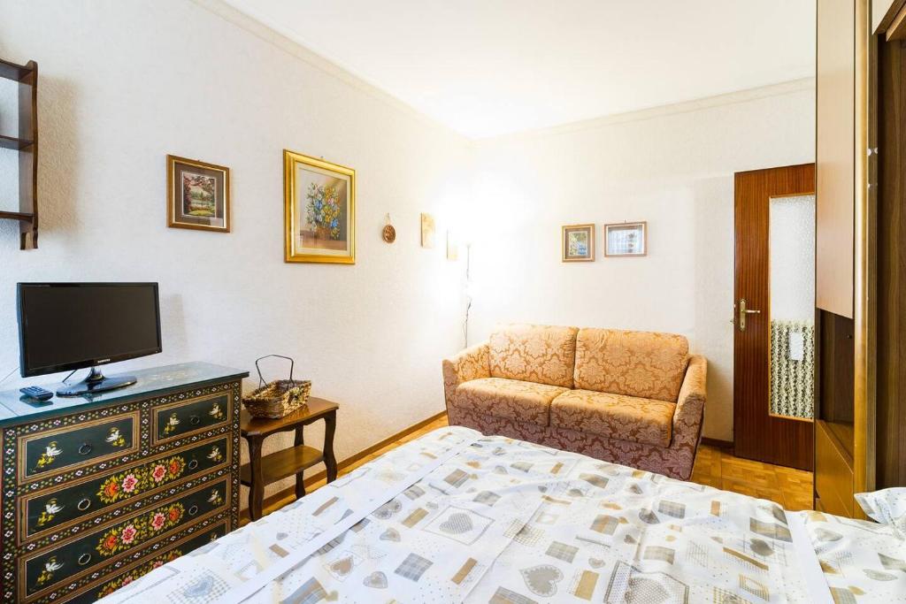 a bedroom with a bed and a chair and a television at Grazioso appartamentino a due passi dalla pista ciclabile con Giardino e Garage in Sanremo