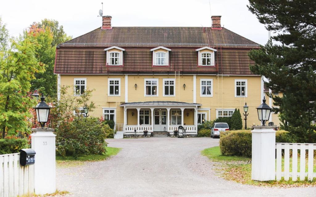 una gran casa amarilla con una valla blanca en Korstäppans Herrgård, en Leksand