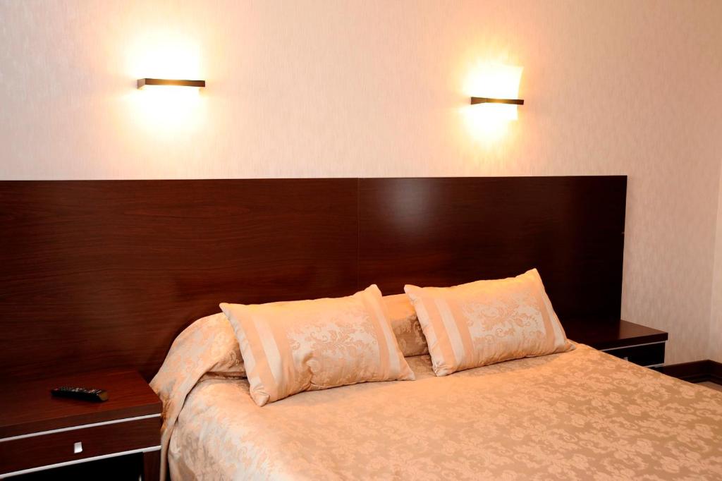 Ce lit se trouve dans une chambre d'hôtel dotée de 2 lumières sur le mur. dans l'établissement Kristall Hotel, à Dmitrov