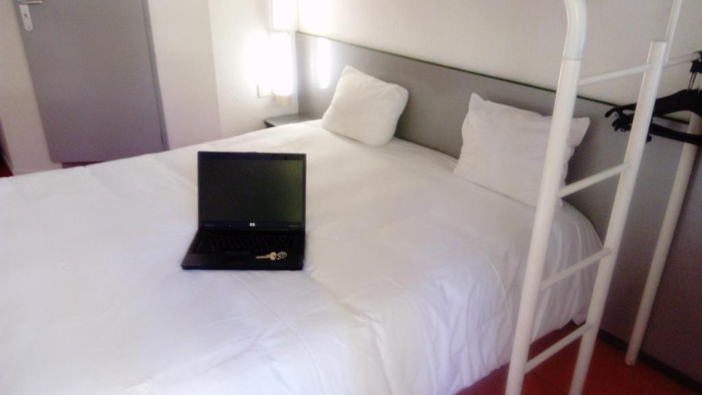 a laptop computer sitting on top of a bed at Premiere Classe Périgueux - Boulazac in Boulazac