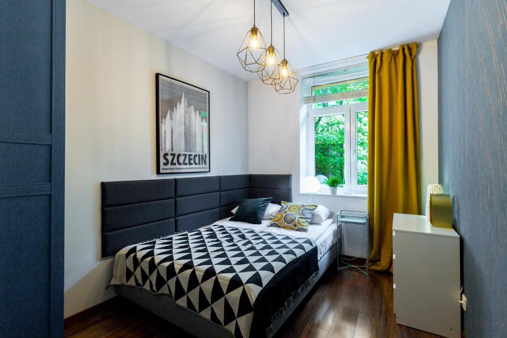 a bedroom with a black and white bed and a window at Wawel Cracow Old City Apartments - Friendhouse Apartments in Krakow