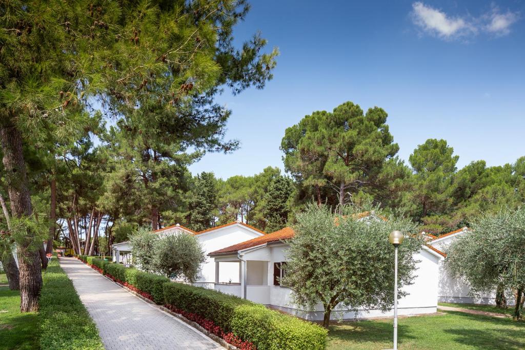 a white house with trees and a sidewalk at Apartments Galijot Plava Laguna in Poreč