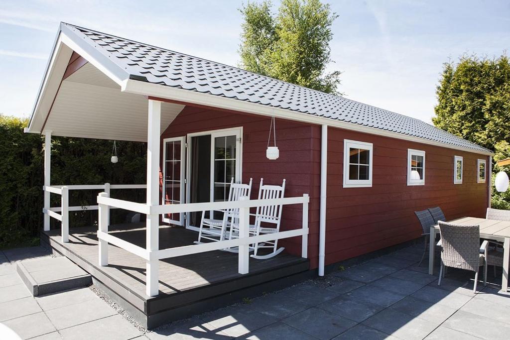 a small red shed with a porch and a table at 6 pers. Veluwelounge + Wellness in Voorthuizen