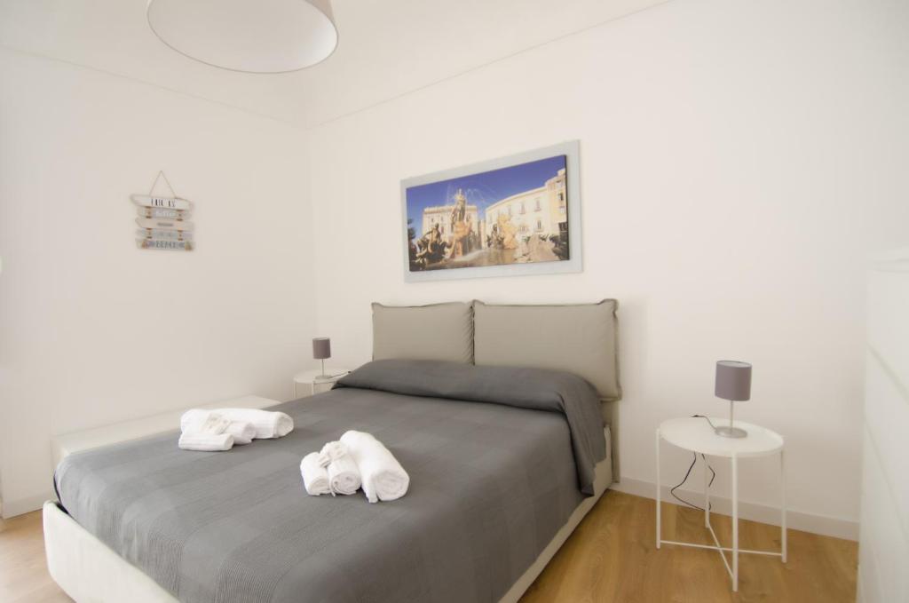 La terrazza di Archimede- Ortigia Holidays في سيراكوزا: غرفة نوم عليها سرير وفوط