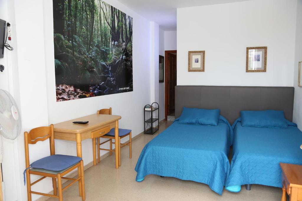 a bedroom with two beds and a table and a desk at Apartamentos Pepita in San Sebastián de la Gomera