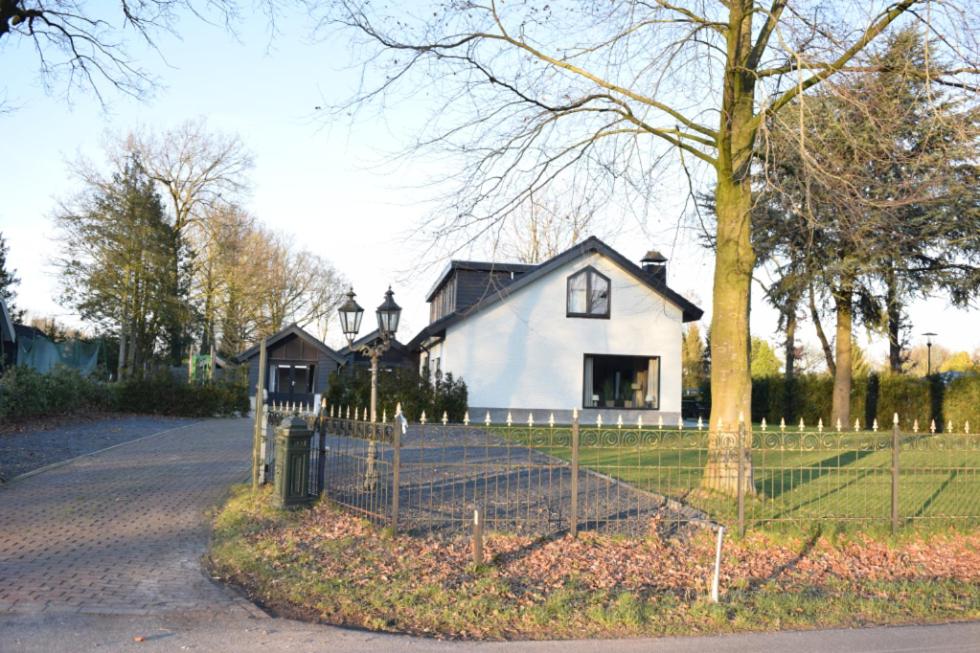 uma casa branca com uma cerca à frente. em Groeps Villa 24 pers. em Voorthuizen