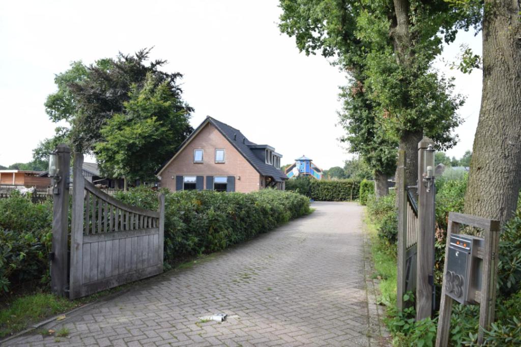 a driveway leading to a house with a wooden gate at Groepsboerderij 20 pers. in Voorthuizen