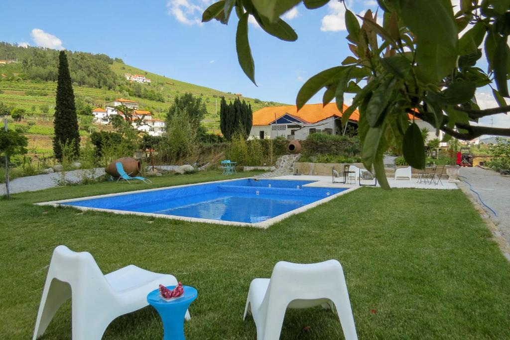 a backyard with a swimming pool and two white chairs at Quinta São José - Museu do Triciclo in Mesão Frio