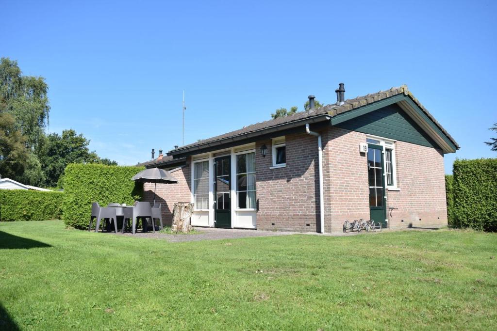 a brick house with a lawn in front of it at Heuveltjes 4 pers. bungalow in Voorthuizen