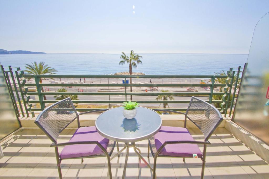 une table et des chaises sur un balcon avec la plage dans l'établissement LES MOUETTES - PROMENADE HOLIDAY, à Nice
