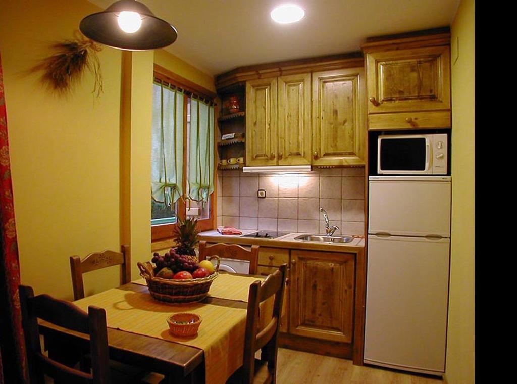a kitchen with a table with a bowl of fruit on it at Apartamentos Los Pirineos - Atencion personal in Biescas
