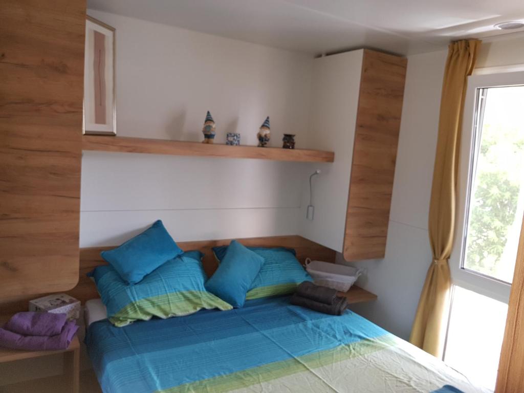 Un dormitorio con una cama con almohadas azules y una ventana en Mobile Home Pearl of Murter en Jezera