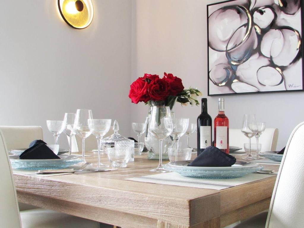 una mesa con copas de vino y un jarrón con rosas rojas en La Citadelle, en Eynesse