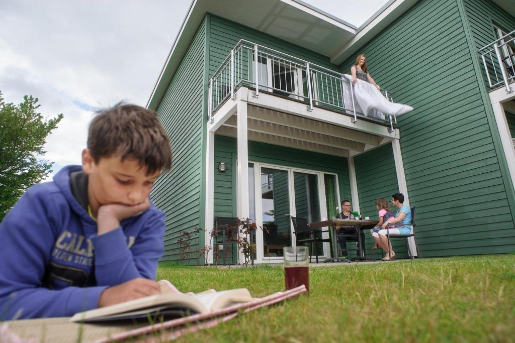 un jeune garçon qui lit un livre devant une maison dans l'établissement Premium Haus, à Damp