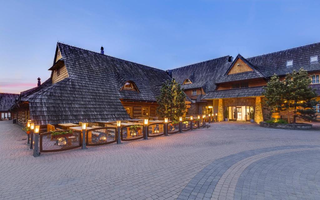 um grande edifício de madeira com luzes à frente em Kocierz Resort - Hotel em Targanice