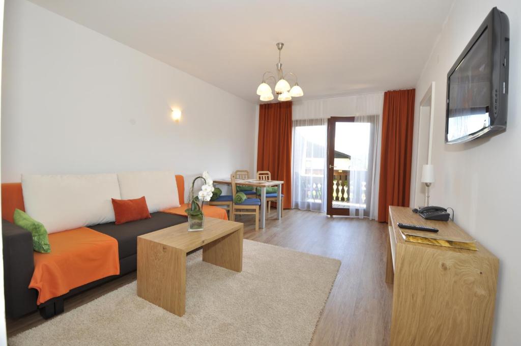 a living room with a couch and a tv at Hotel Garni Wurzer in Velden am Wörthersee