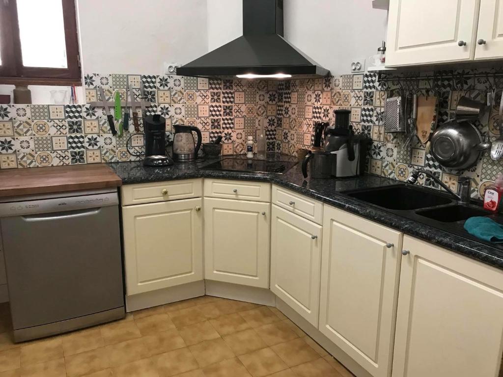 a kitchen with white cabinets and a sink at Chez les Amis in Saint-Nazaire-de-Ladarez