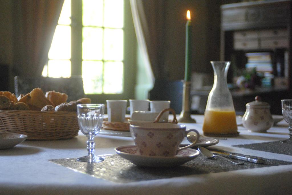 a table with a table cloth with cups and a glass at Le Ragois in Richelieu