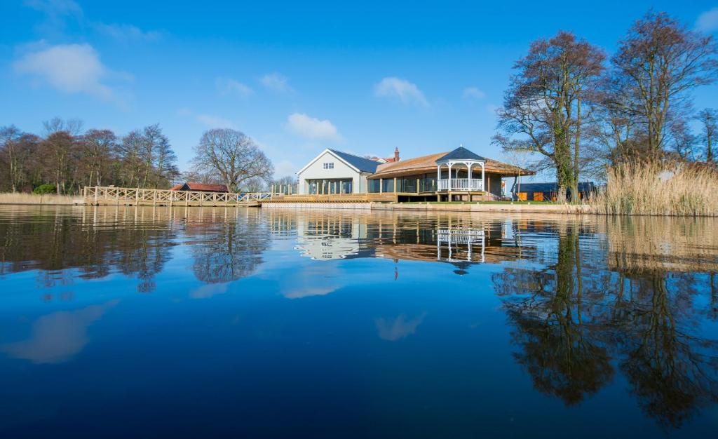 a house sitting on the shore of a lake at The Boathouse in Rollesby