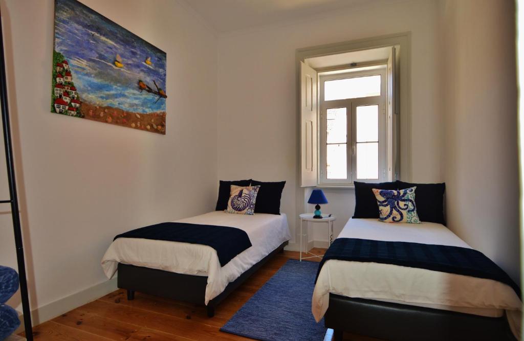 a bedroom with two beds and a painting on the wall at Casa Joana B&B in Cascais