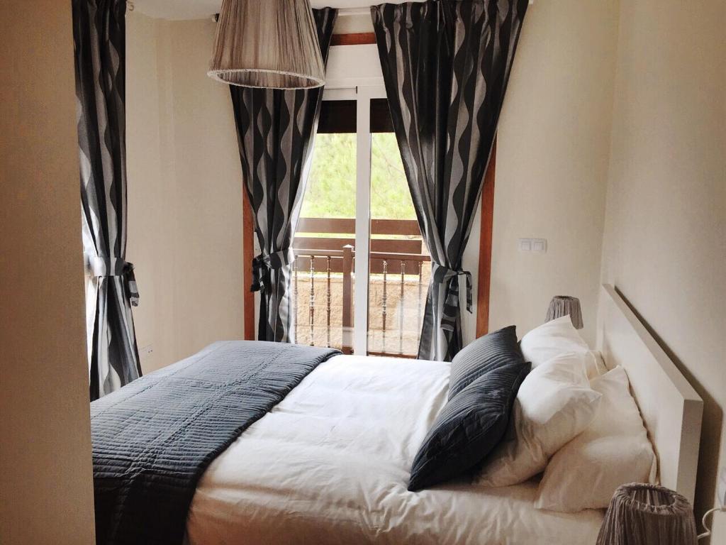 1 dormitorio con cama con almohadas y ventana en Apartamento Mirador de Corrubedo en Corrubedo