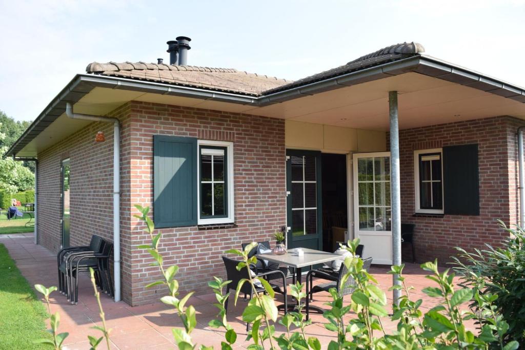 a brick house with a patio and a table at Wilbrink 6-8 pers. bungalow in Voorthuizen