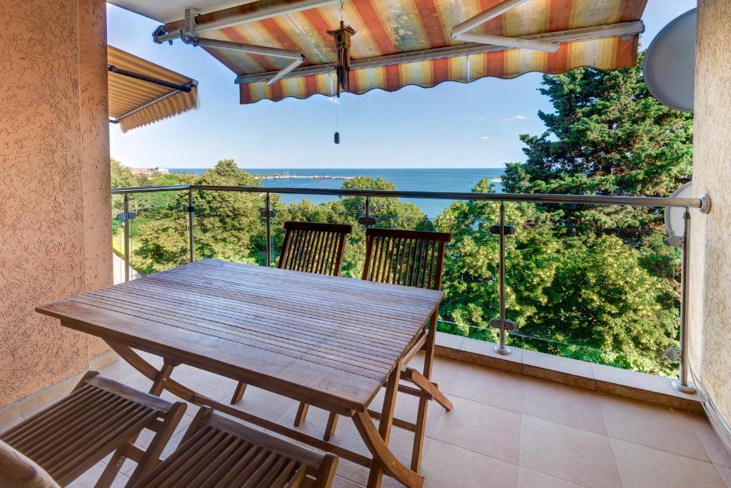 a wooden table and chairs on a balcony with a view at ДриймБг Апартаменти - Панорама Бийч, Несебър in Nesebar