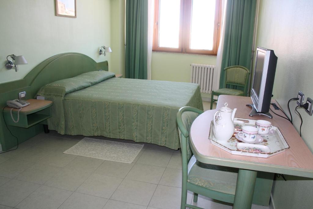 ヌーオロにあるHotel Grilloのベッド、テーブル、テレビが備わる客室です。