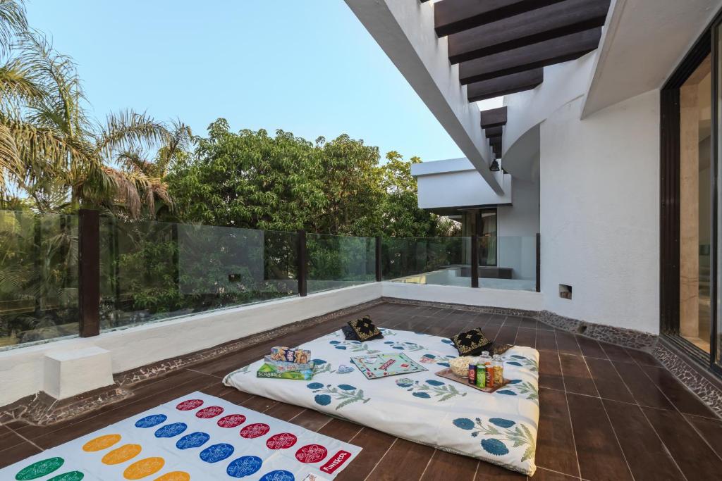 a patio with three blankets on the floor of a house at SaffronStays Vedanta, Lonavala - villa with lawn, plunge pool and indoor games near Tungarli Lake in Lonavala