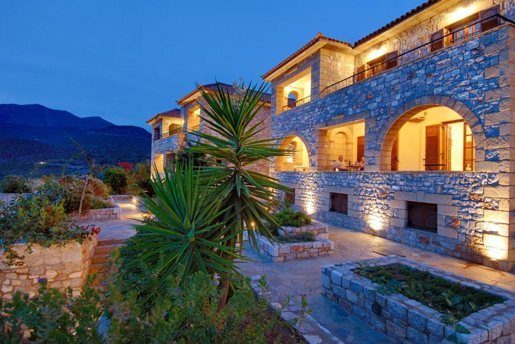 a large stone house with a palm tree in front of it at Vardia Hotel in Kardamyli