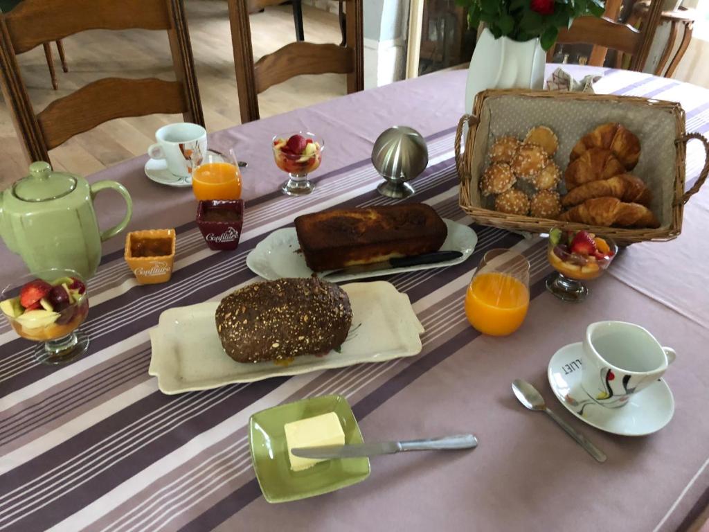 een tafel met een ontbijt van brood en jus d'orange bij Chambres D'hôtes le clos de la Bertinière petit déjeuner inclus in Bosgouet