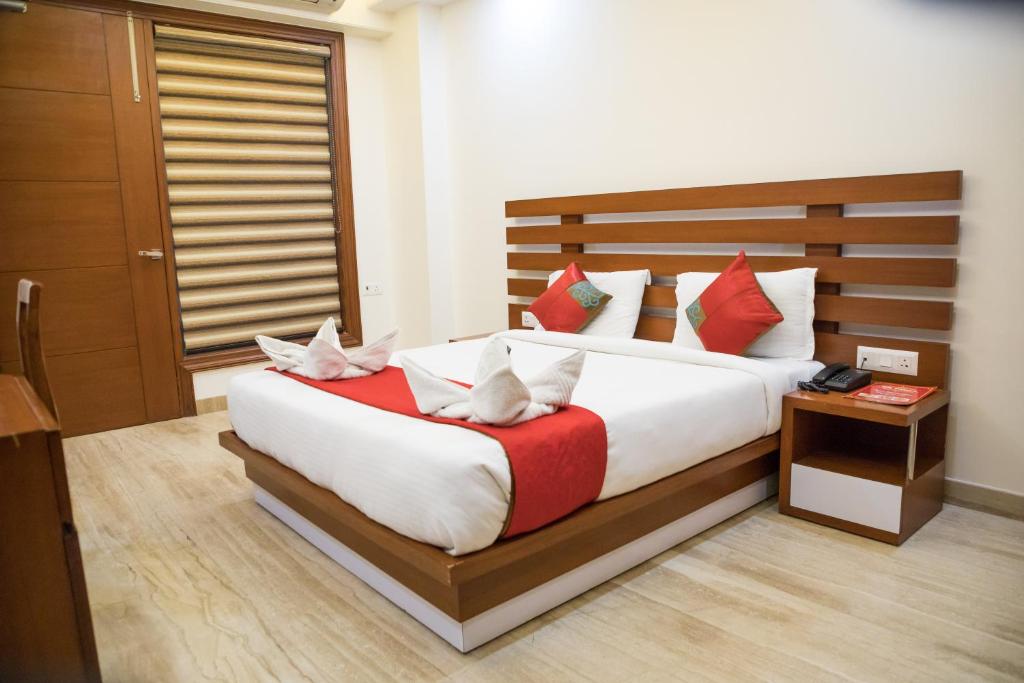 um quarto com uma cama grande e almofadas vermelhas e brancas em SM Palace (Near Apollo Hospital) em Nova Deli