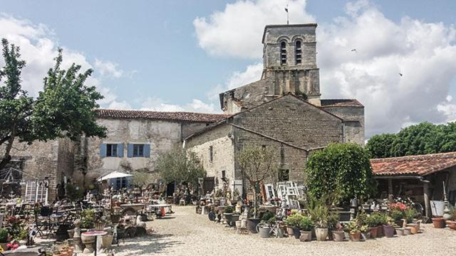 un vieux bâtiment avec une église et une tour d'horloge dans l'établissement Le vieux Prieuré, à Cressé