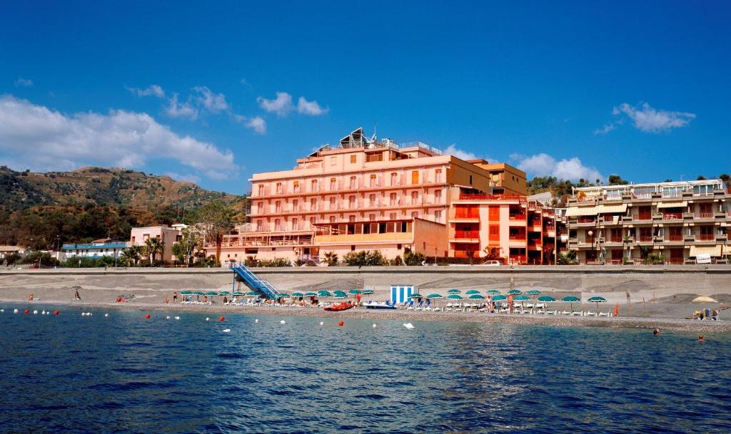 una spiaggia con un grande edificio e un hotel di Hotel Kennedy a SantʼAlessio Siculo