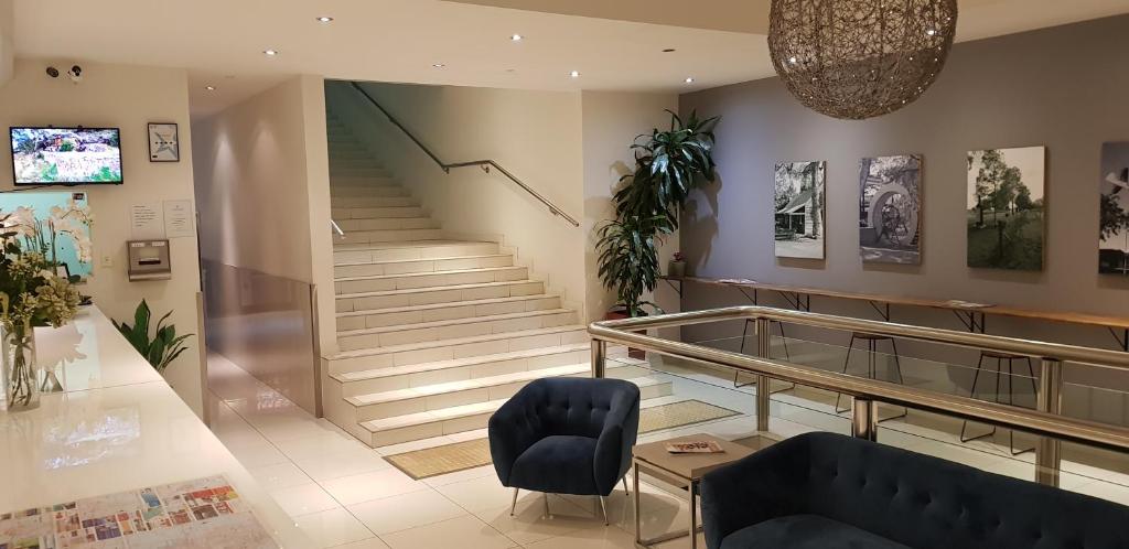 eine Lobby mit einer Treppe, einem blauen Sofa und einem Glastisch in der Unterkunft The Grand Motel in Griffith