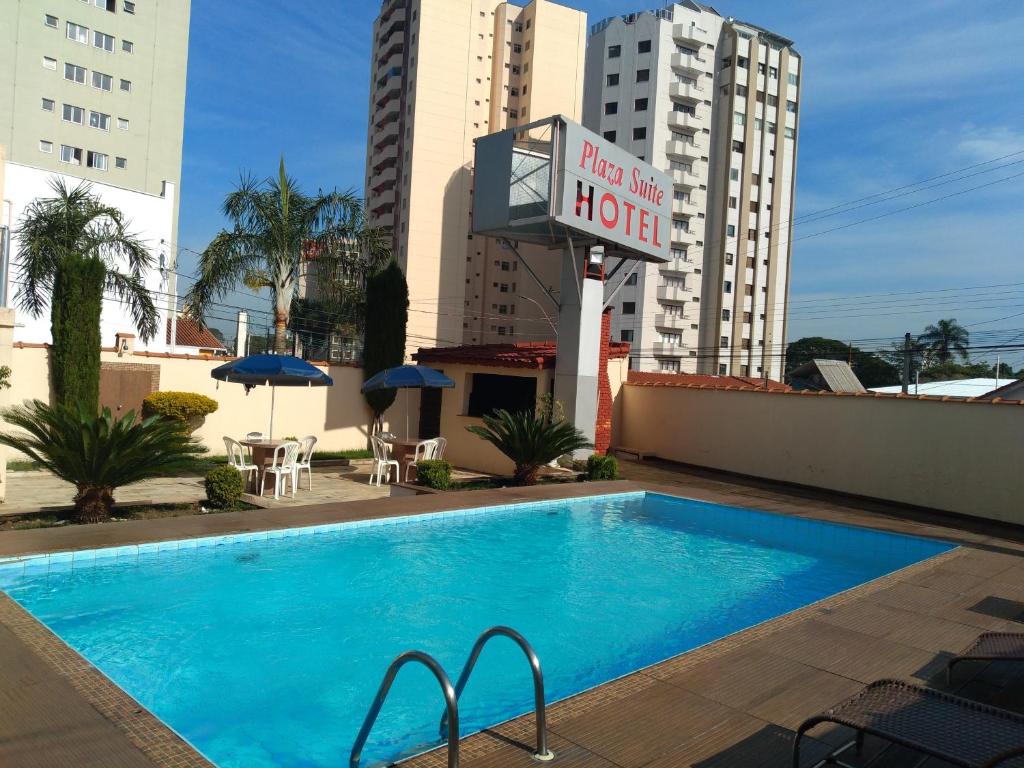 a hotel with a swimming pool and a hotel sign at Plaza Suite Hotel Ltda in Taubaté