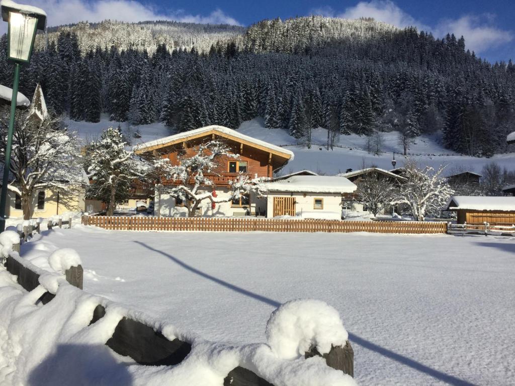 einen schneebedeckten Hof mit einem Gebäude im Hintergrund in der Unterkunft Wagnerhäusl in Bramberg am Wildkogel