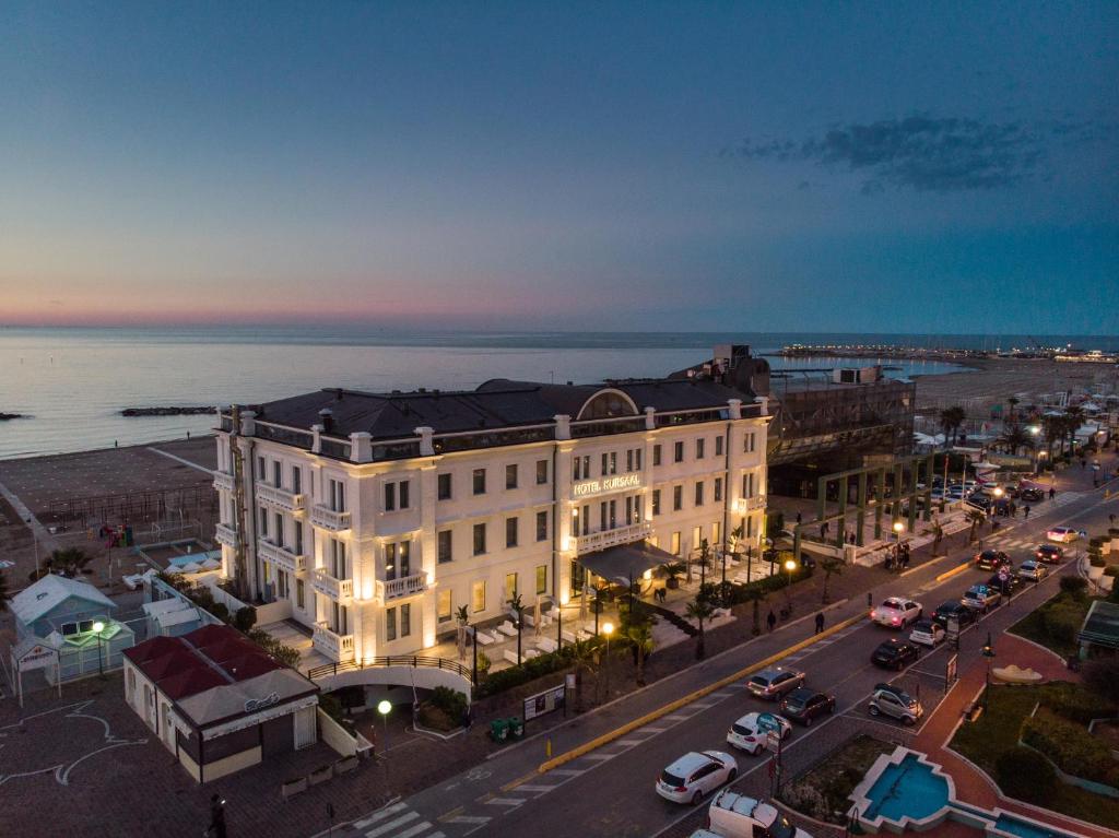 a large white building on a city street at night at Kursaal Hotel in Cattolica