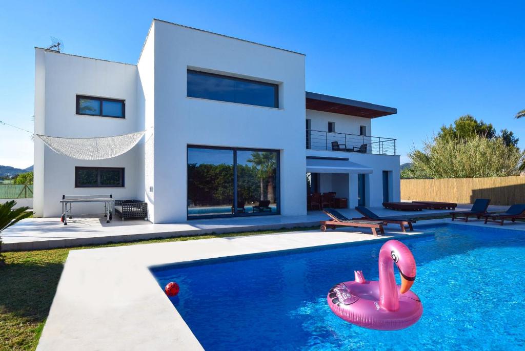 a house with a swimming pool with a pink flamingos in front at Can miami modern house close platja den bossa in Sant Jordi