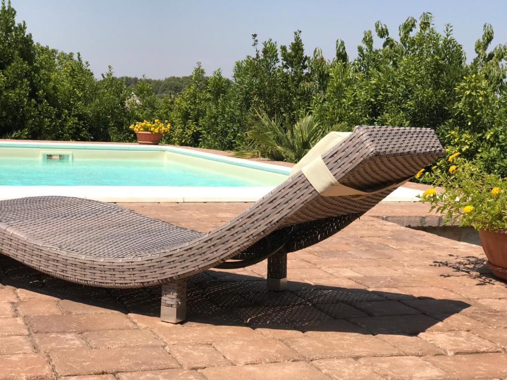 una sedia in rattan seduta accanto alla piscina di Trullo delle Querce Suite Private Pool a Martina Franca