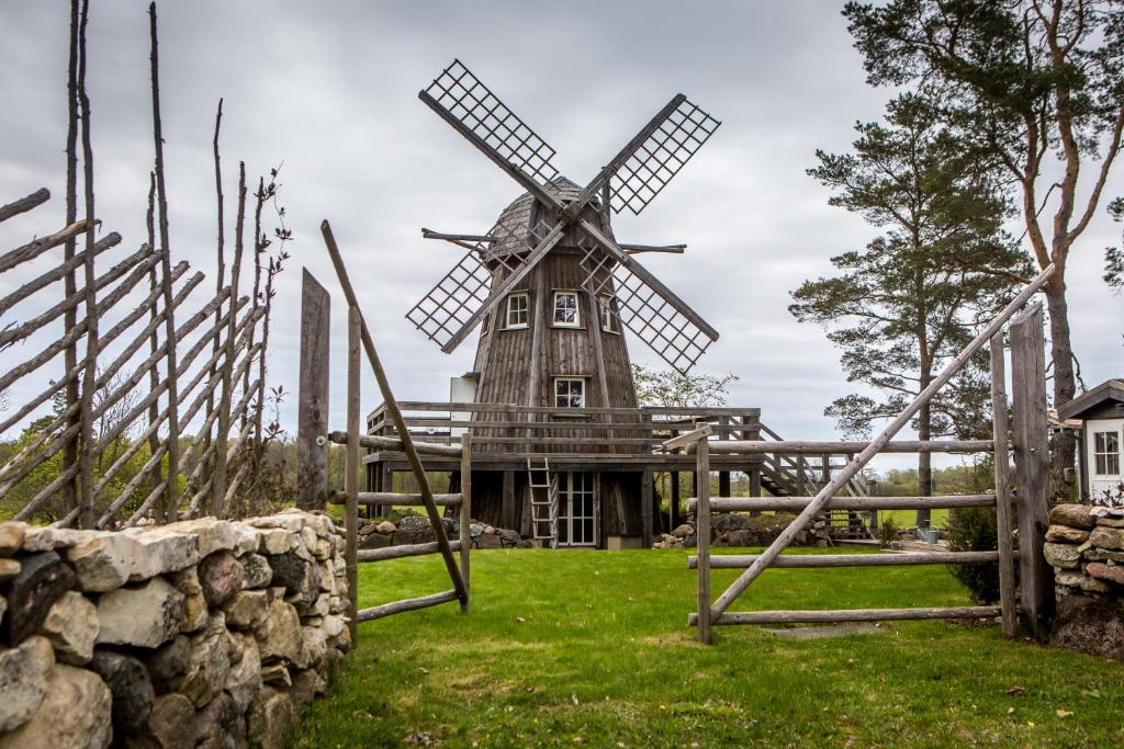 a wooden windmill in a field with a fence at Windmill - Summer house in Mõega