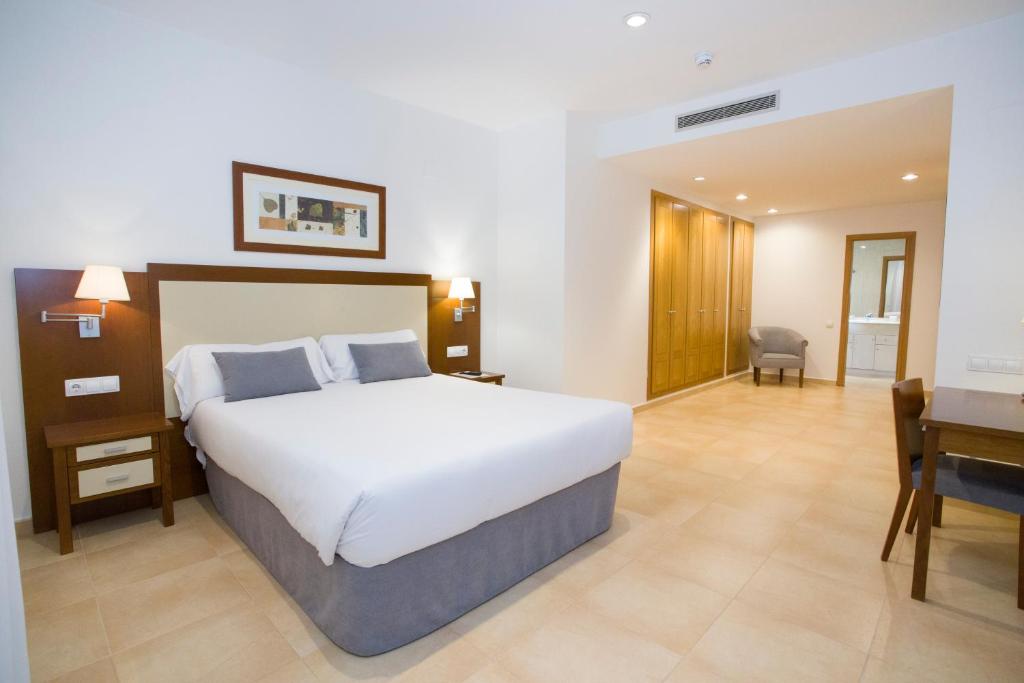 a bedroom with a large white bed and a desk at Aparthotel Albufera in Alfafar