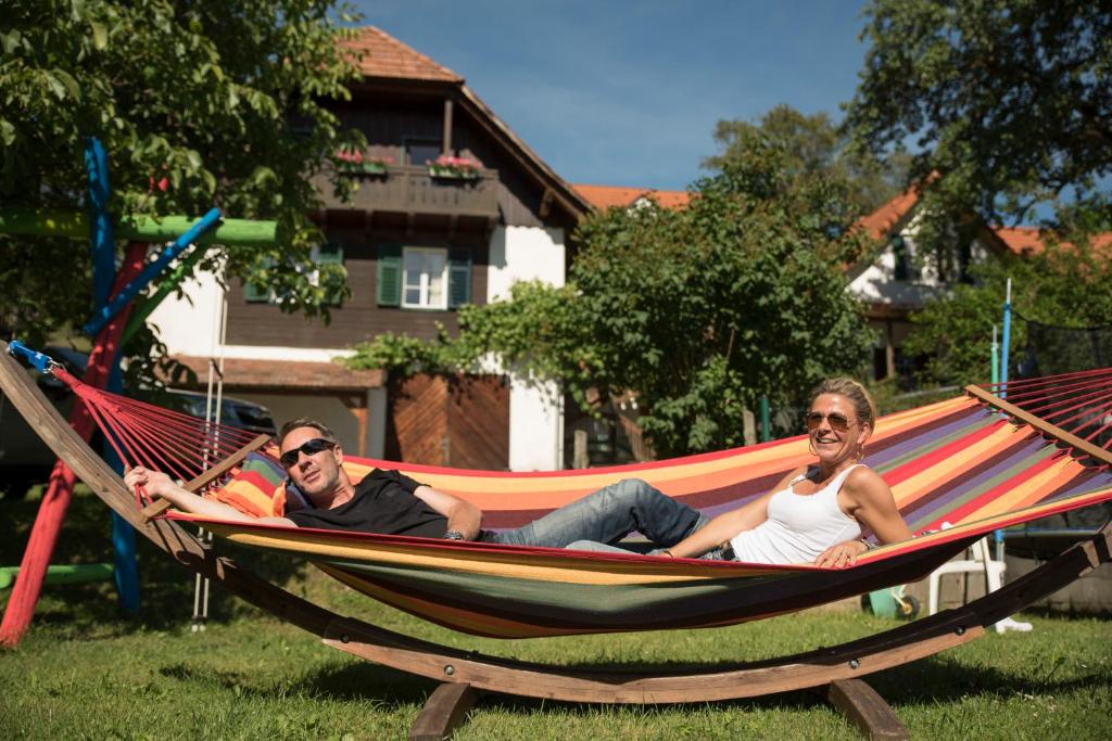 due uomini sdraiati su un'amaca in un giardino di Bio-Hof Windhaber a Stubenberg