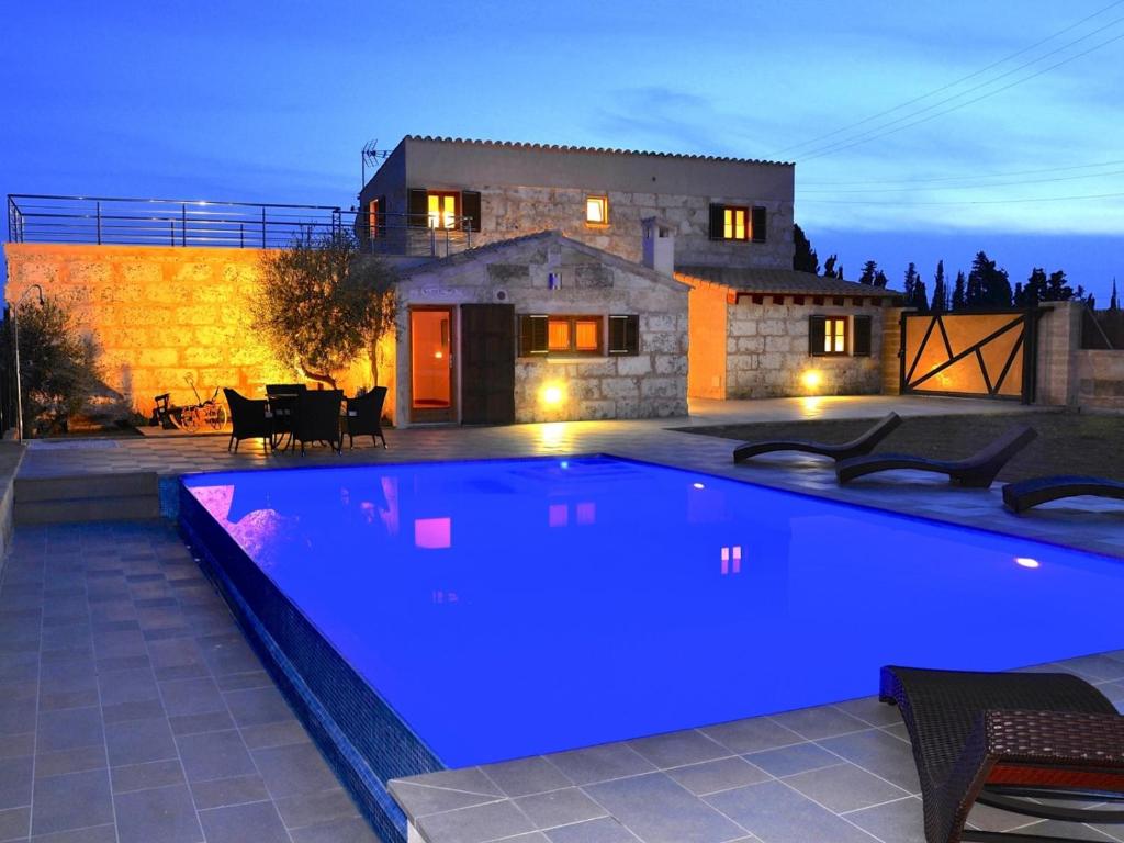 a blue swimming pool in front of a house at Vinagrella in Llubí