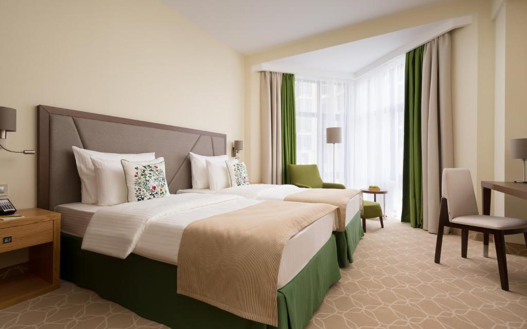 キスロヴォツクにあるGreen Resort Hotel and SPAのベッド2台とデスクが備わるホテルルームです。