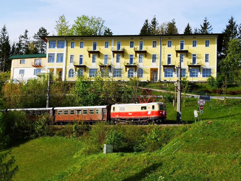 un train sur les voies devant un bâtiment dans l'établissement Hotel Restaurant Winterbach, à Sankt Anton an der Jessnitz