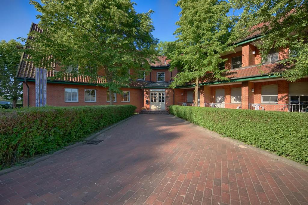 a red brick building with a driveway leading to it at Hotel & Gasthof Zur Linde in Middelhagen