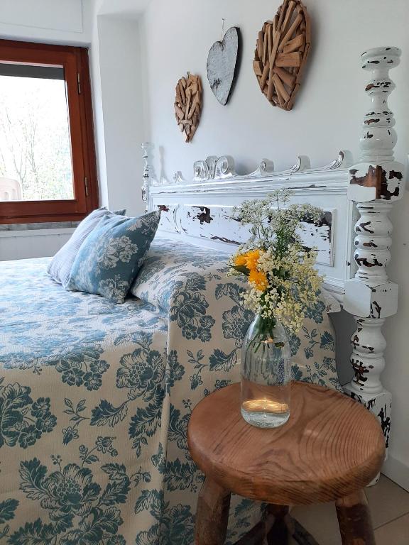 una camera da letto con un letto e un vaso di fiori su un tavolo di B&B dei Laghi a Magreglio